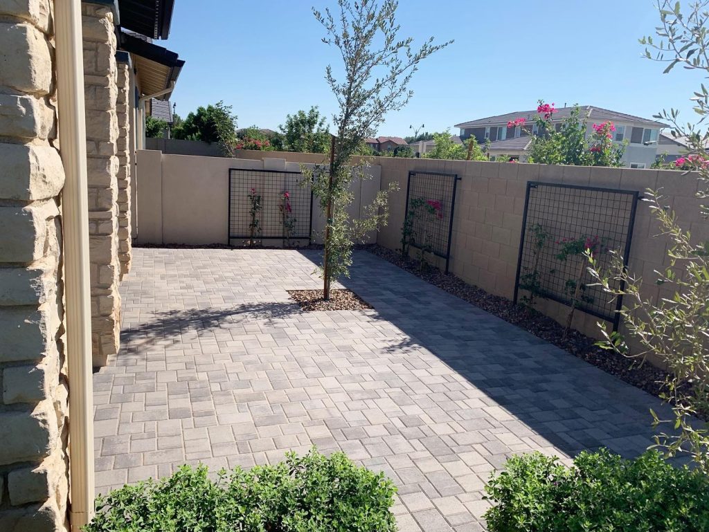 a beautiful paver backyard with metal trellises