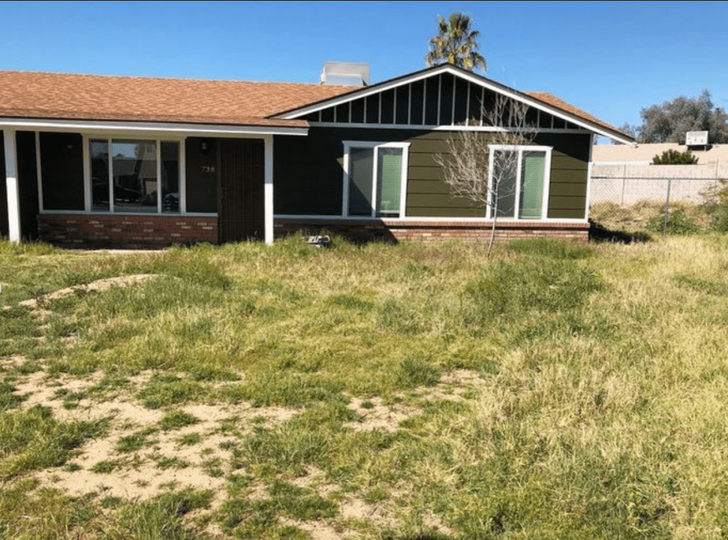 an overgrown yard with patchy grass and dirt