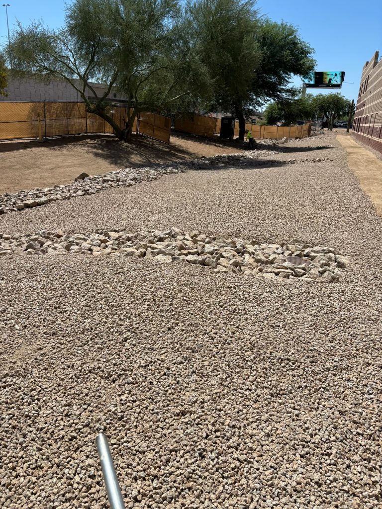 after photo of a large commercial drainage area professionally landscaped with river rocks and granite